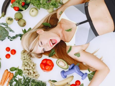 Vrouw met een salade en fitnessmateriaal op tafel