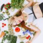 Vrouw met een salade en fitnessmateriaal op tafel